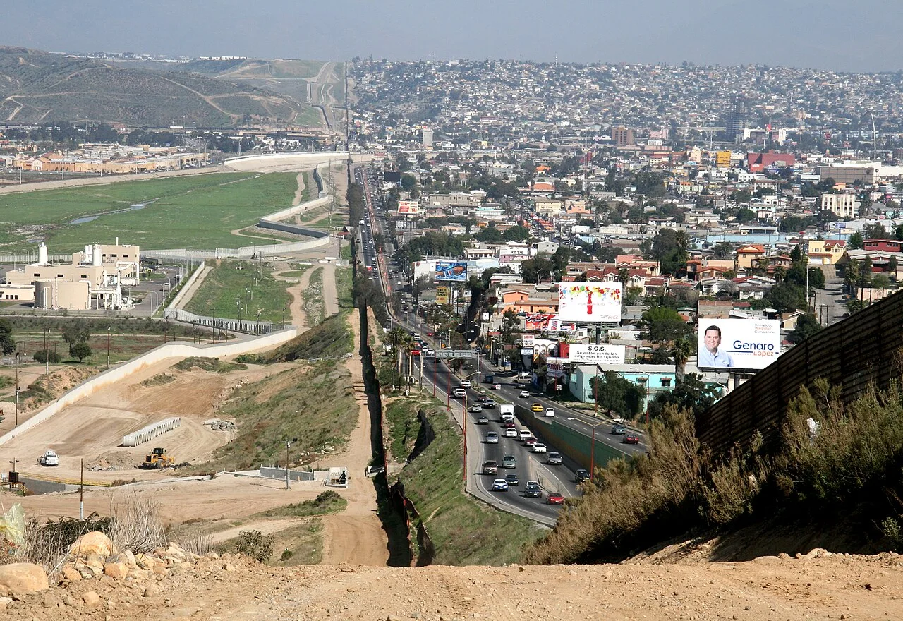 A small fence separates densely-populated Tijuana, Mexico, right, from the United States in the Border Patrol's San Diego Sector. Construction is underway to extend a secondary fence over the top of this hill and eventua