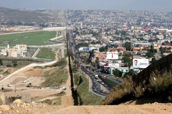 A small fence separates densely-populated Tijuana, Mexico, right, from the United States in the Border Patrol's San Diego Sector. Construction is underway to extend a secondary fence over the top of this hill and eventua
